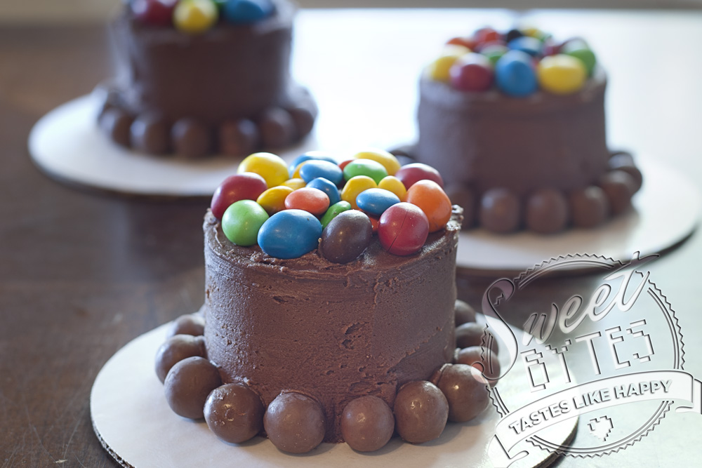 Mini Cakes decorated with m&m's on top and whoppers around the bottom