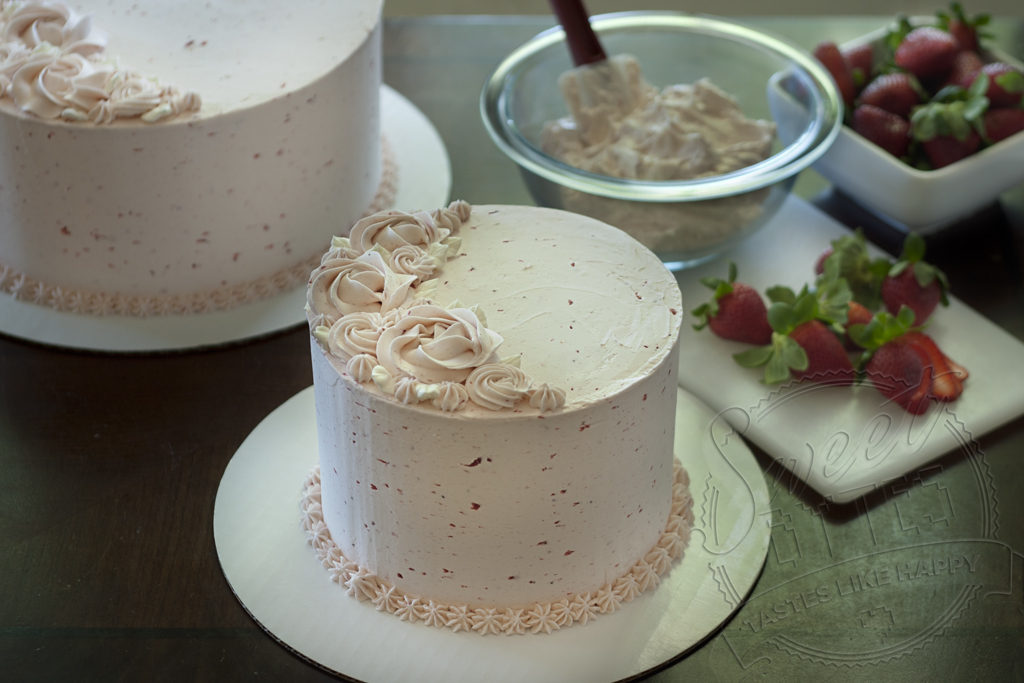 an overhead picture of a made from scratch strawberry cake with a crescent of piped buttercream decorations on top.