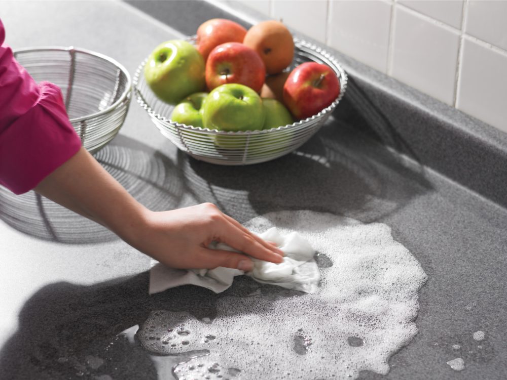 a hand washing a countertop with sudsy water