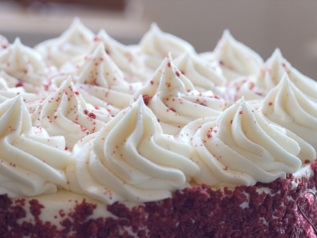 Peaks of cream cheese frosting on top of a red velvet cake