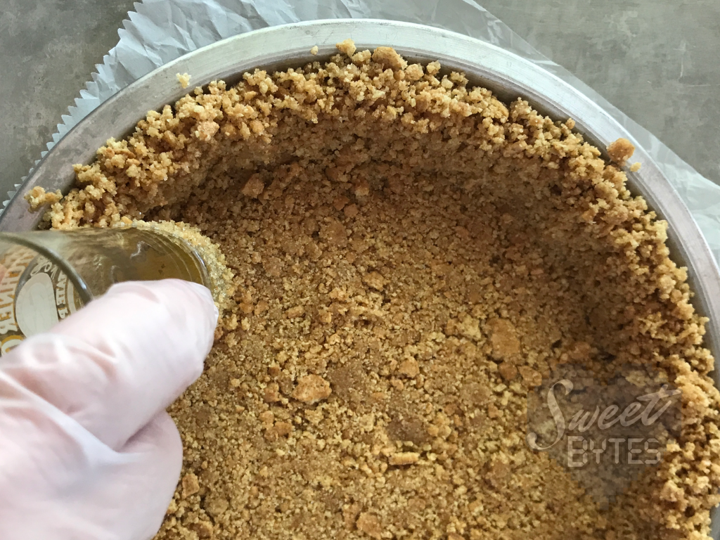 A close up of a graham cracker crust being made in a pie pan