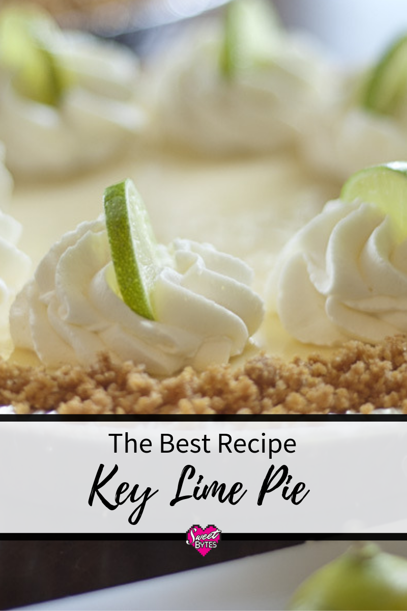 The BEST Key Lime Pie Recipe close up of the top of a key lime pie with whipped cream and key lime slices.