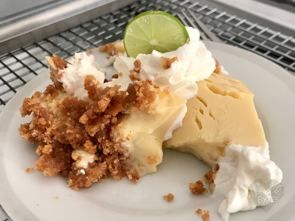 A terribly disfigured slice of key lime pie on a white dessert plate