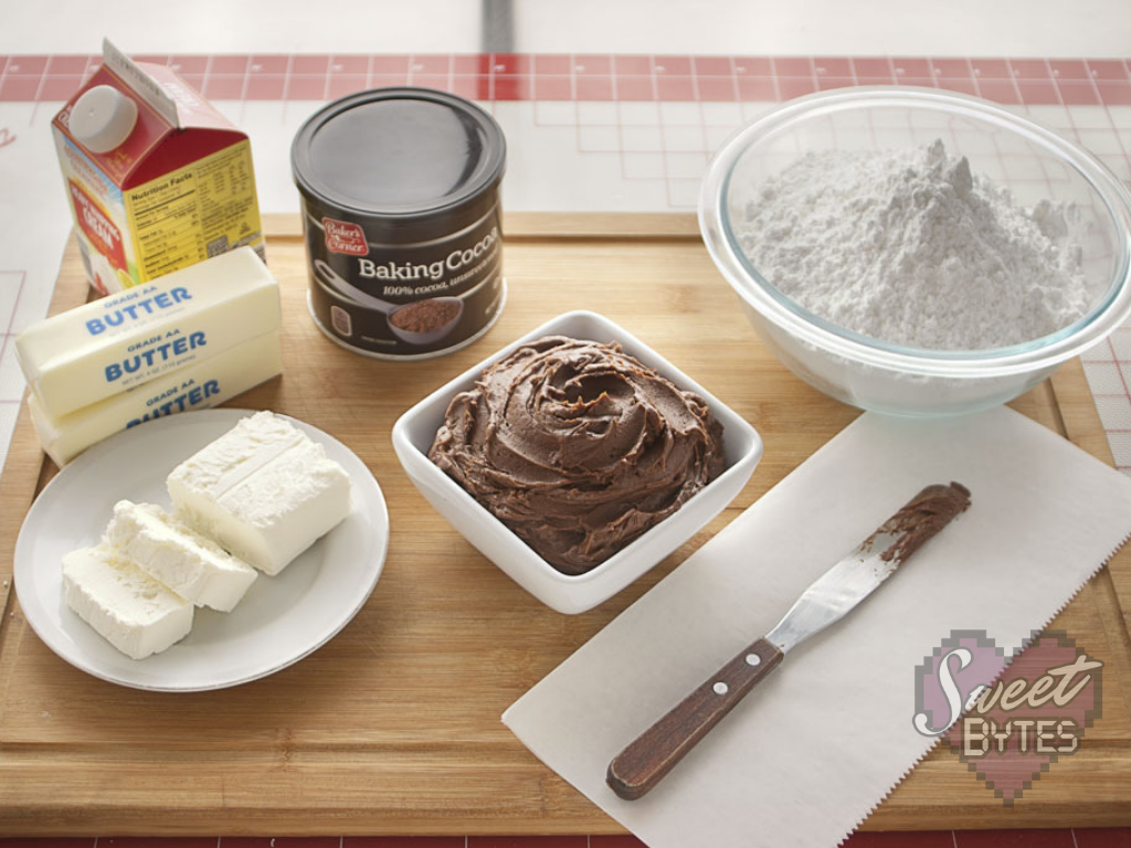 A small, white, square bowl of chocolate cake frosting surrounded by the recipe's ingredients