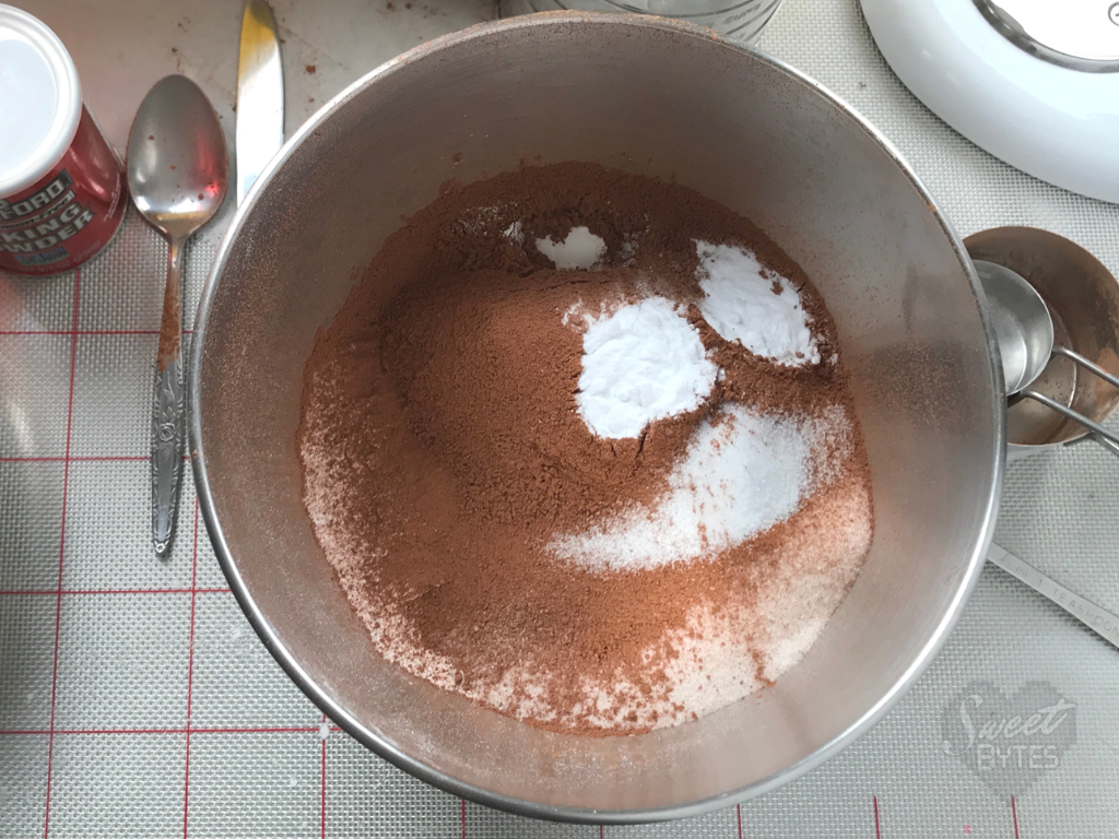 Dry ingredients go first into your mixing bowl when making this chocolate cake recipe from scratch by Sweet Bytes OKC Large stainless steel mixing bowl with dry ingredients for the chocolate cake recipe inside