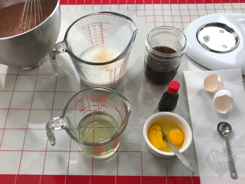 Mise en place the wet ingredients for this chocolate cake recipe from scratch Overhead photo of measuring cups filled with wet ingredients for the chocolate cake arranged on a gridded silicon mat
