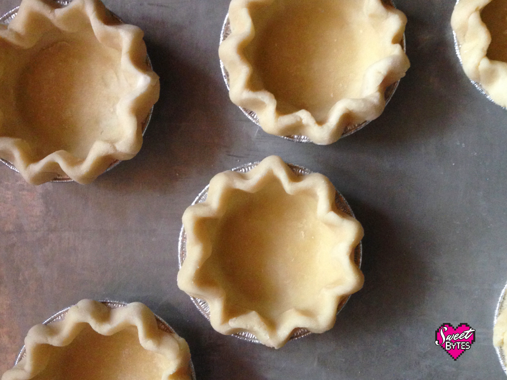 Overhead shot of 5 mini pie crusts arranged on a cookie sheet for baking pie crust