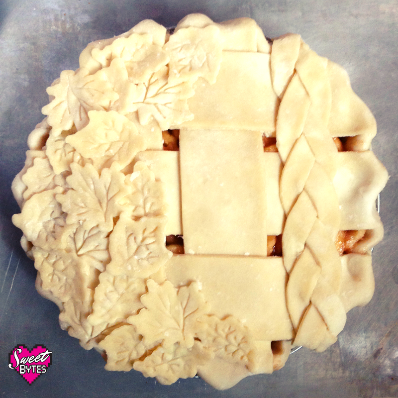 An uncooked apple pie with pie crust leaves and a braided pie crust