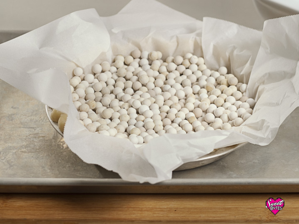 a raw pie crust lined with parchment paper and filled with ceramic pie weights for parbaking pie crust for pumpkin pie