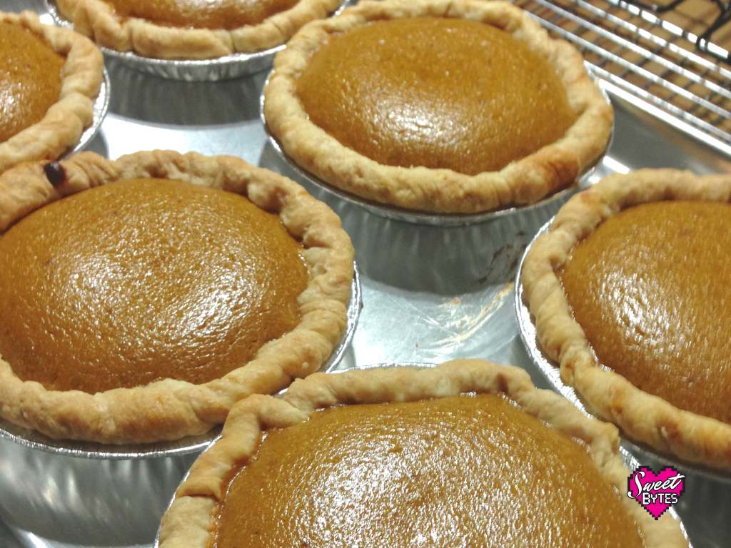 Baking sheet with six small pumpkin pies fresh out of the oven