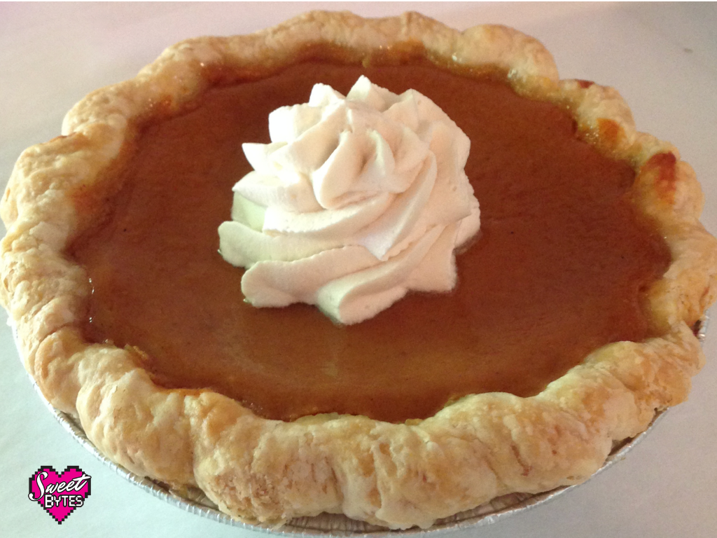 A baked pumpkin pie with a swirl of whipped cream in the center.