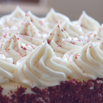 Peaks of cream cheese frosting on top of a red velvet cake