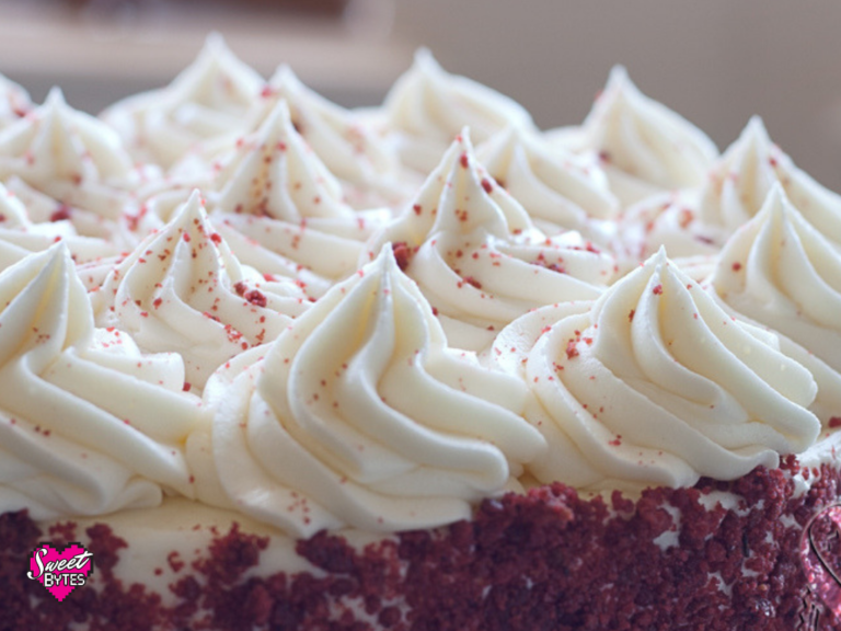 Peaks of cream cheese frosting on top of a red velvet cake