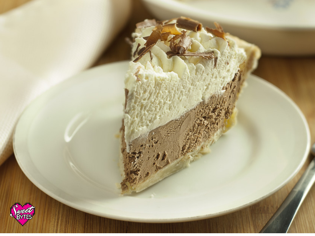 Slice of French Silk Pie with whipped cream and chocolate curls on top arranged on a white plate.