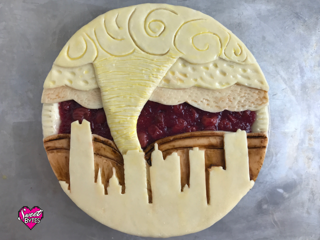 Cherry pie with a decorative pie crust showing downtown oklahoma city with a tornado in the background
