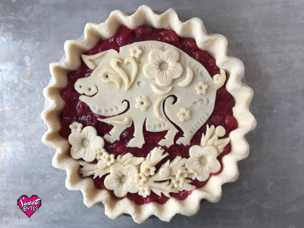 Unbaked cherry pie with flowers and a decorative pig celebrating Lunar New Year