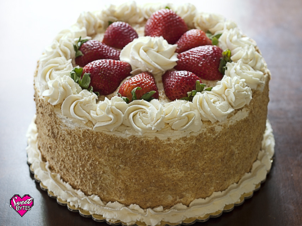 A strawberry and cream cake on with piped mascarpone whipped cream and strawberries on tip