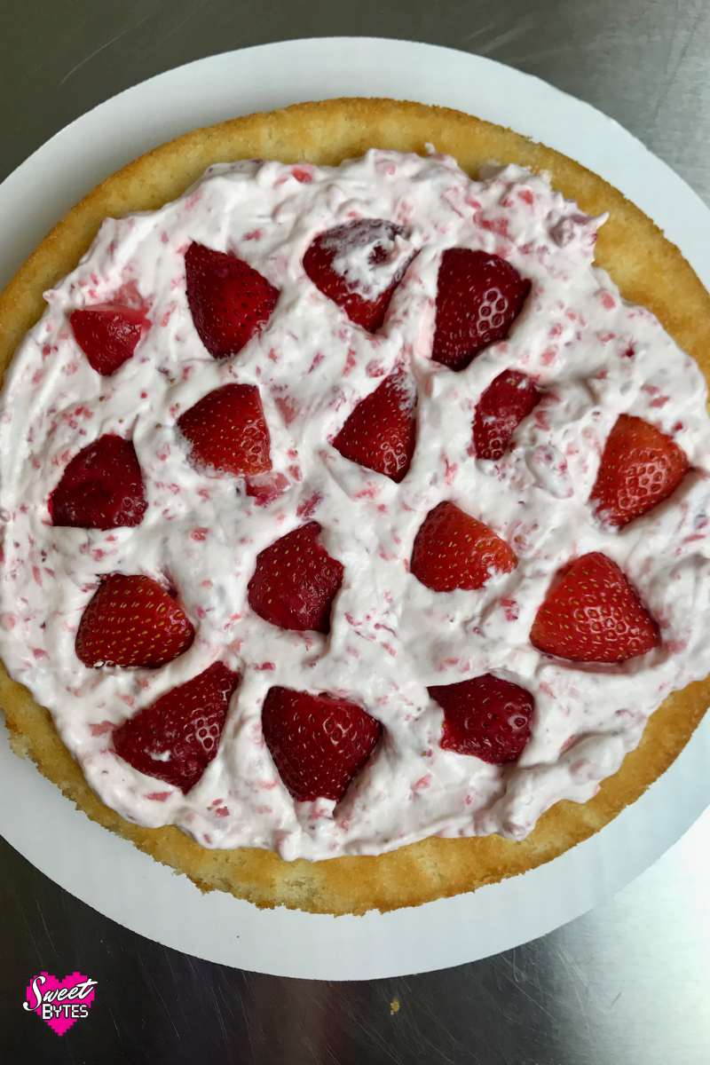 Inside view of strawberry and cream layer cake. Cake layer with strawberry and cream and quartered strawberries. 