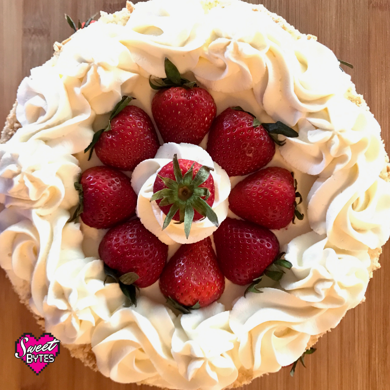 A top view of strawberry and cream cake with fresh strawberries place around the top