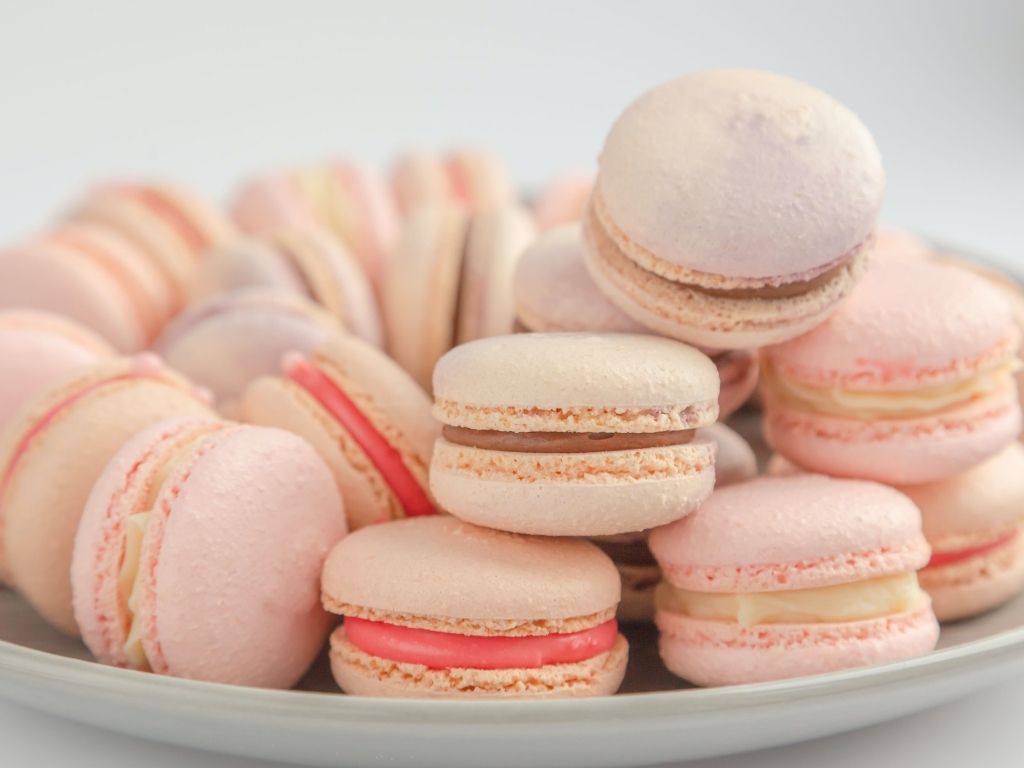 Plate full of pink macarons with different colored fillings