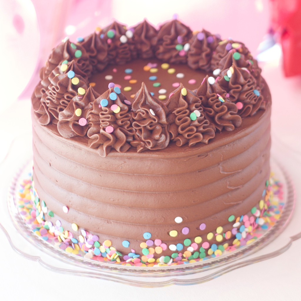 A chocolate cake with chocolate buttercream and confetti sprinkles on top
